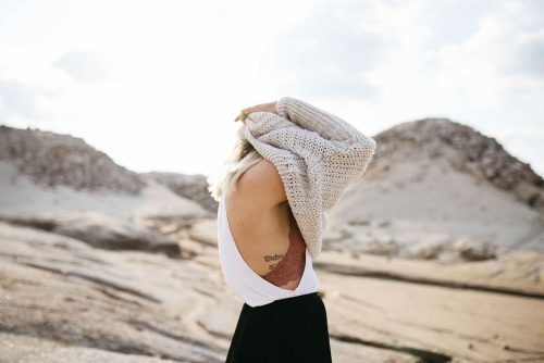 woman pulling sweater over her head 