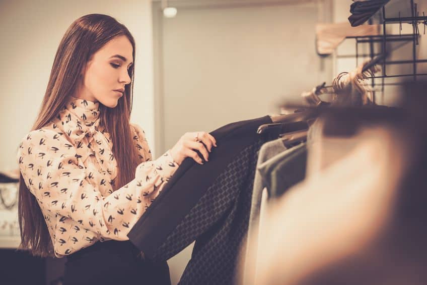 young woman choosing clothes on a rack in a showroom