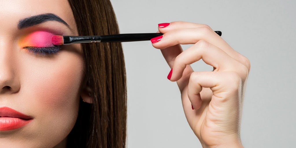 Woman applying pink eyeshadow with a makeup brush