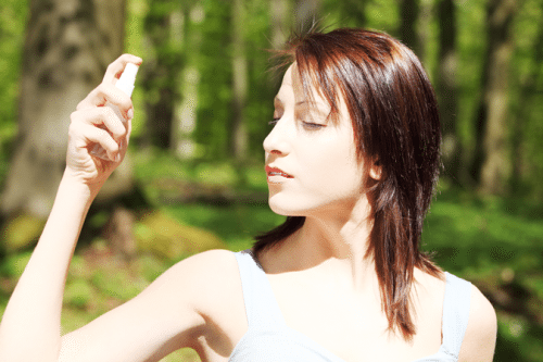 woman outside spraying herself with mist